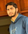 Young man with a beard wearing a blue hoodie, looking thoughtfully to the side.