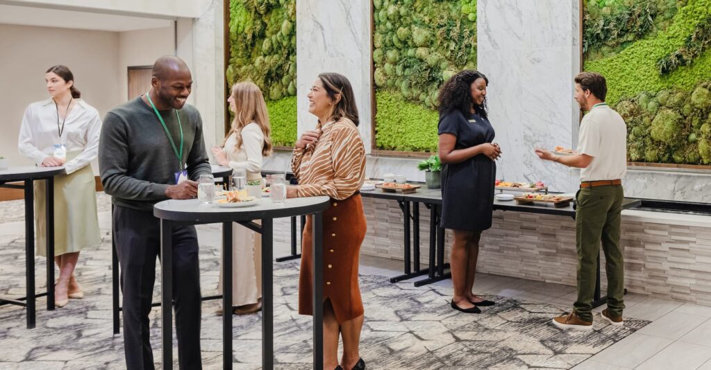 Professionals networking during a breakfast break at a conference, with a vibrant living wall providing a fresh backdrop.